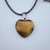 Close-up of a Tiger's Eye heart pendant showing the natural chatoyant bands and rich amber-gold colors.