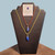 Two Lapis Lazuli tumble pendants on yellow and orange cords displayed with a leadership and expression informational card.
