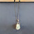 Minimalist silver-toned metal nest pendant designed to hold tumbled stones and crystals.