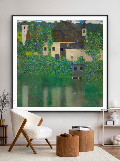 An oversized square fine art print of Gustav Klimt’s Schloss Kammer on the Attersee I, styled in a contemporary residential living room. The large print hangs in a thin black frame on a light wall directly behind a white boucle accent chair and two cylindrical wood side tables.
