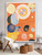 Large abstract artwork with spirals and circular motifs in warm orange, yellow, blue, and pink tones displayed in a modern living room with neutral furniture