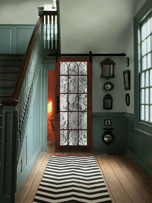 lifestyle of hallway sliding barn door wood frame arched wood grid and mercury mirrored glass