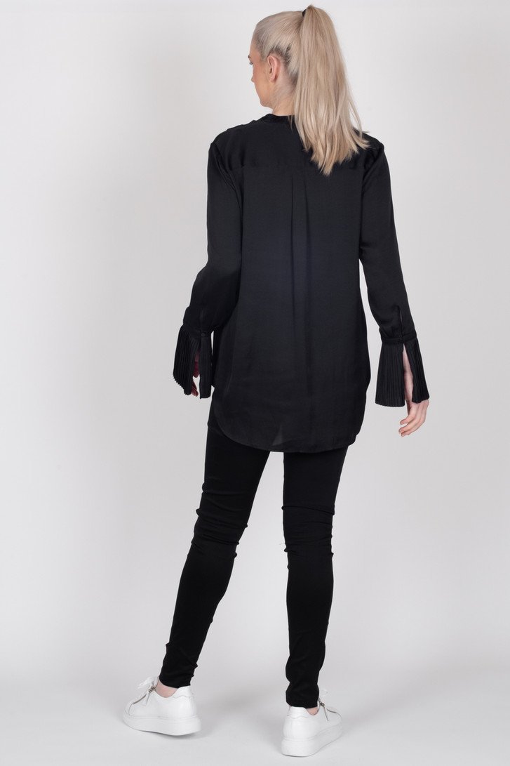 Tall woman showing back length of the untucked Storm black satin Paloma Shirt